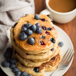 Blueberry Cornbread Pancakes on a Plate with Coffee Cup in the Background