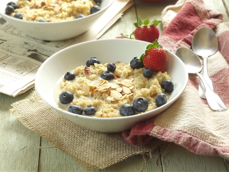 Two bowls of breakfast quinoa porridge with berries and almonds on top.