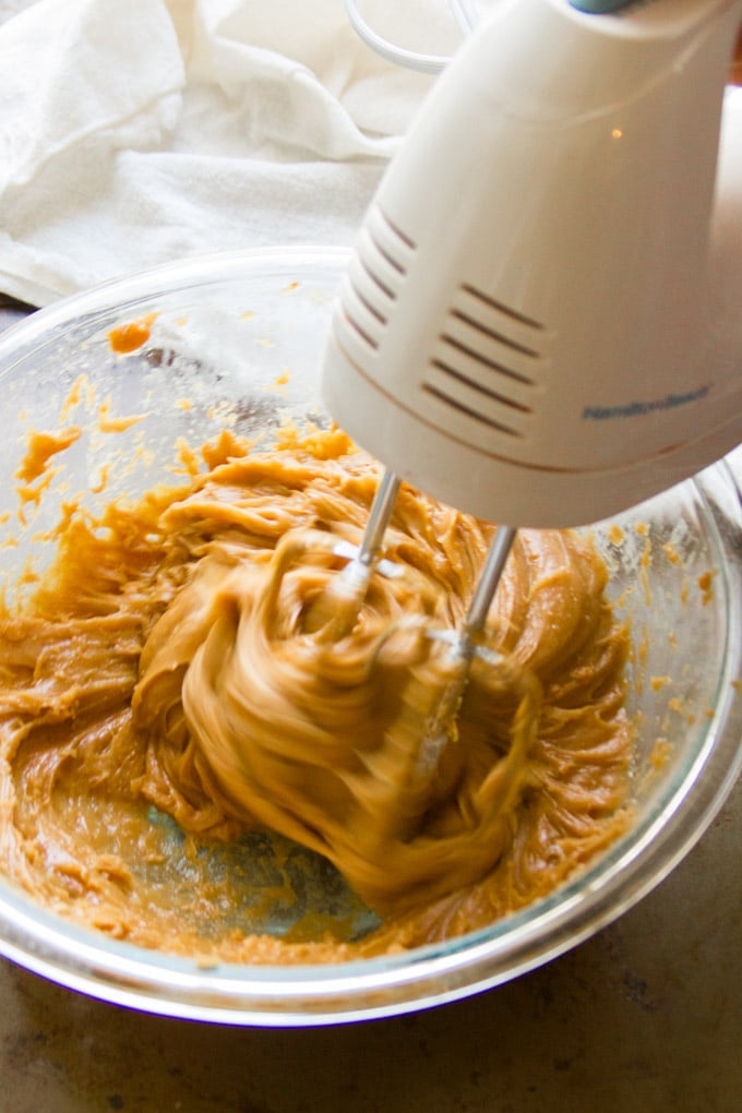Hand Mixer Beating Peanut Butter Frosting in a Glass Mixing Bowl for Making Chocolate Peanut Butter Cupcakes