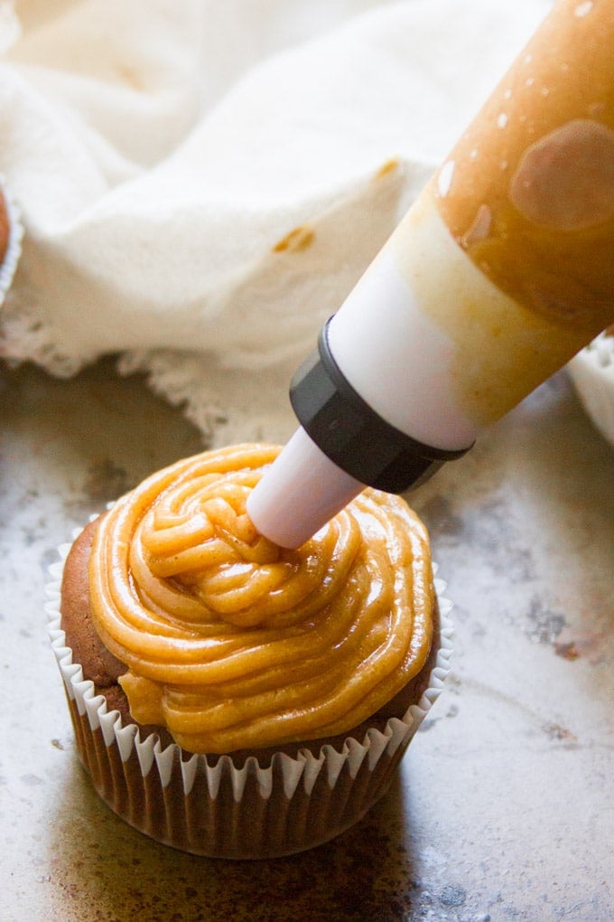 Pastry Bag Piping Peanut Butter Frosting Onto a Chocolate Cupcake