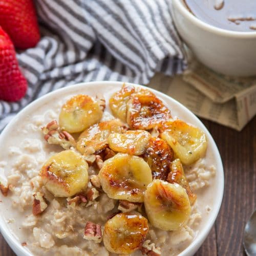 A Bowl of Caramelized Banana Oatmeal with Coffee Cup and Strawberries in the Background