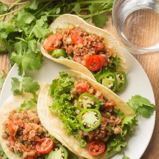 Wooden Table Set with a Plate of Lentil Quinoa Tacos, Skillet and Water Glass