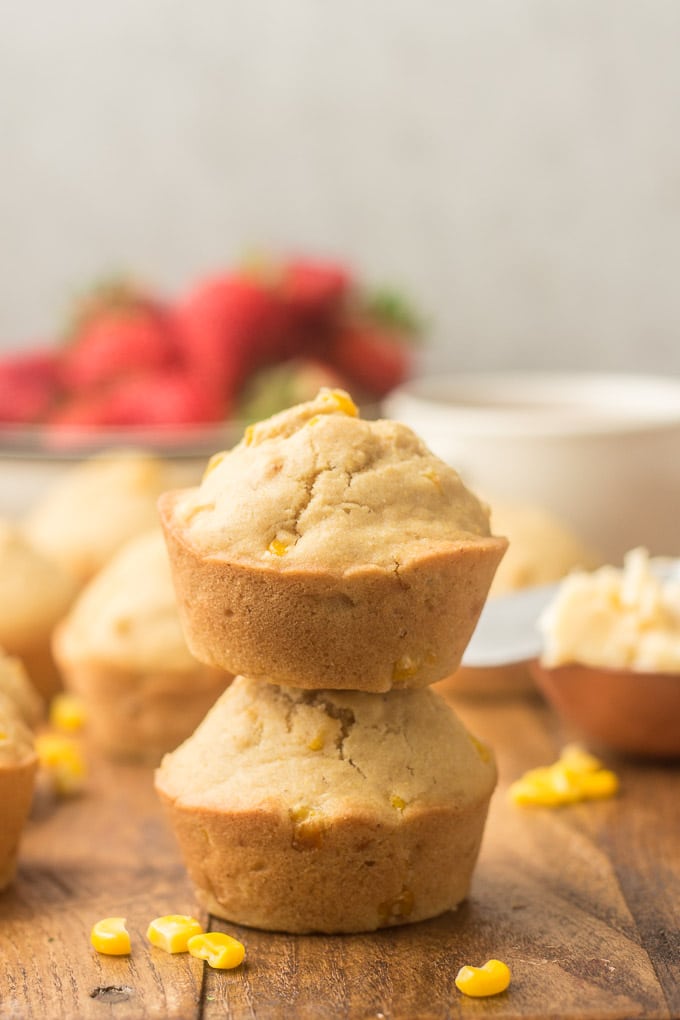 Two Stacked Vegan Corn Muffins with Strawberries, Muffins and Tea Cup in the Background