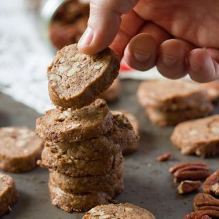 Hand Picking Up the Top Cookie From a Stack of Vegan Pecan Shortbread Cookies