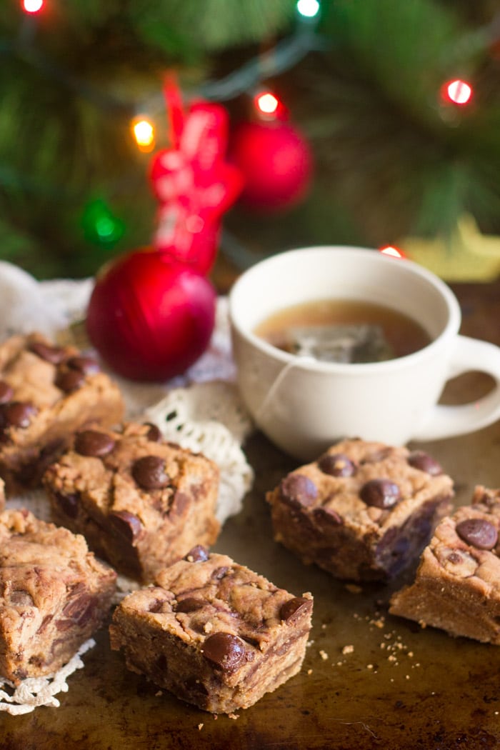 Chocolate Chunk Cookie Butter Blondies and a Cup of Tea with a Lit Christmas Tree in the Background