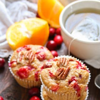 Stack of Two Cranberry Orange Quinoa Muffins with Another Muffin, Teacup and Orange Slices in the Background