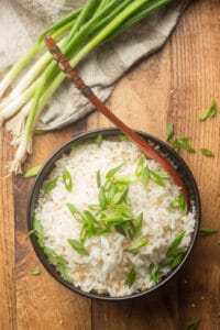 Bowl of Coconut Rice with Serving Spoon and Scallions