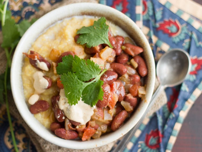 Overhead View of a Bowl of Creamy Polenta and Beans with Spoon on the Side