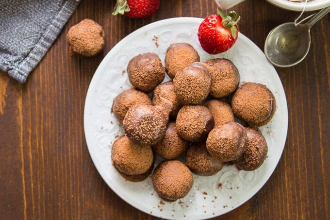 Overhead View of a Plate of Vegan Truffles on a Plate with Strawberries and a Cup of Tea