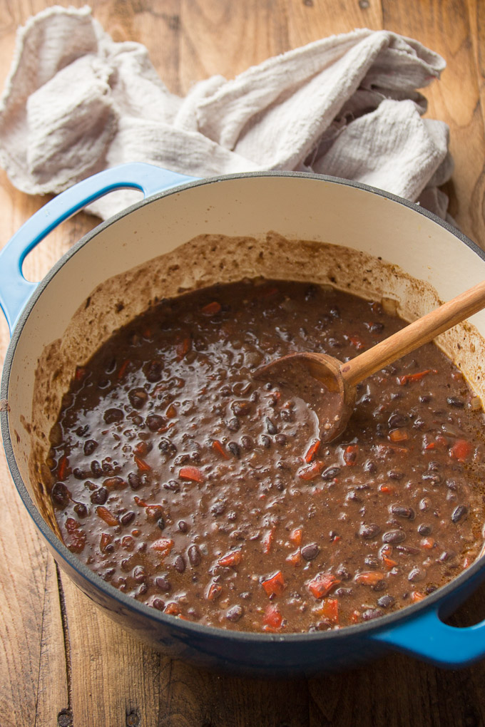 Blue Pot Filled with Spicy Black Bean Soup with a Wooden Spoon