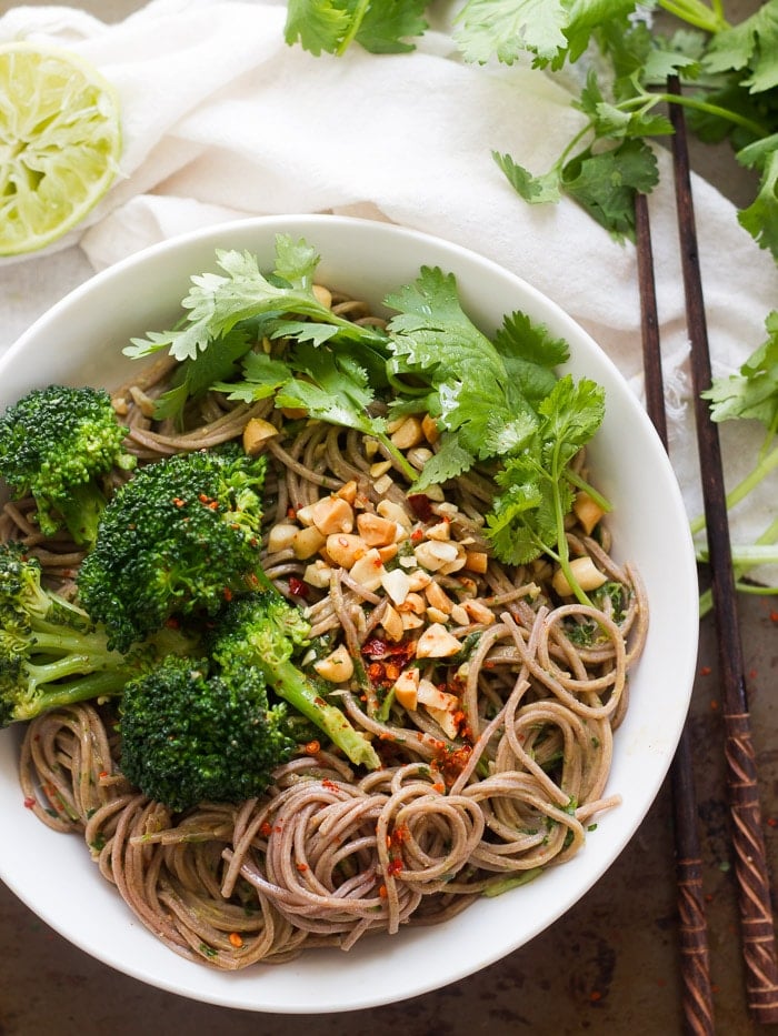 Bowl of Cilantro Peanut Soba Noodles and Broccoli on a Distressed Surface with Cloth and Chopsticks