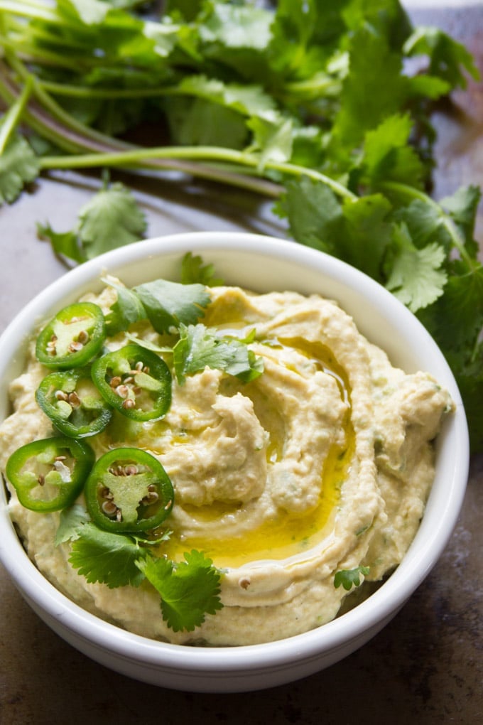 Roasted Jalapeño Hummus in a Bowl with Cilantro in the Background.