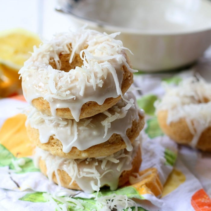 Stack of Three Lemon Doughnuts Topped with Glaze and Coconut Sitting on a Colorful Napkin