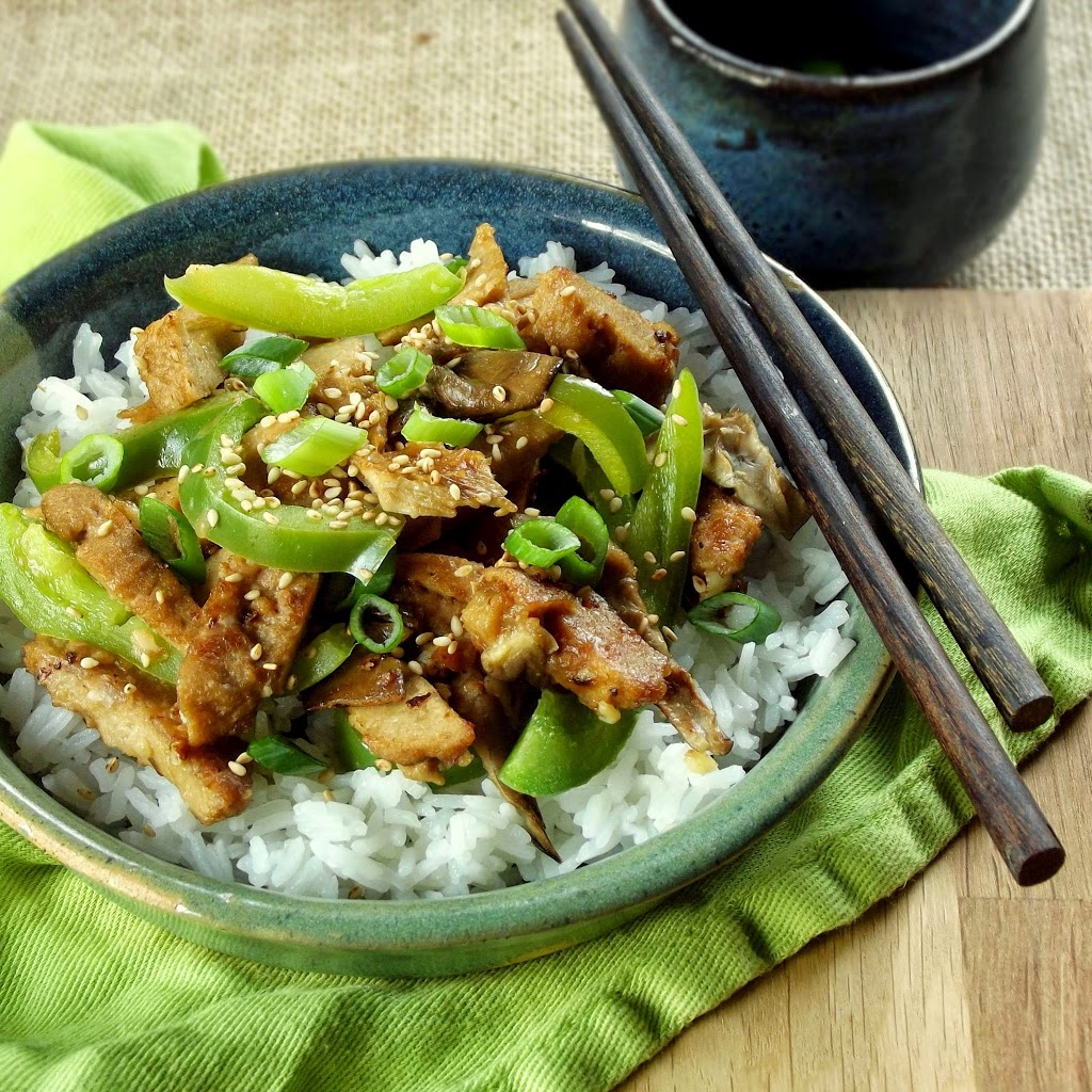 Sesame Seitan and Peppers Over Rice on a Plate with Chopsticks Perched on the Side