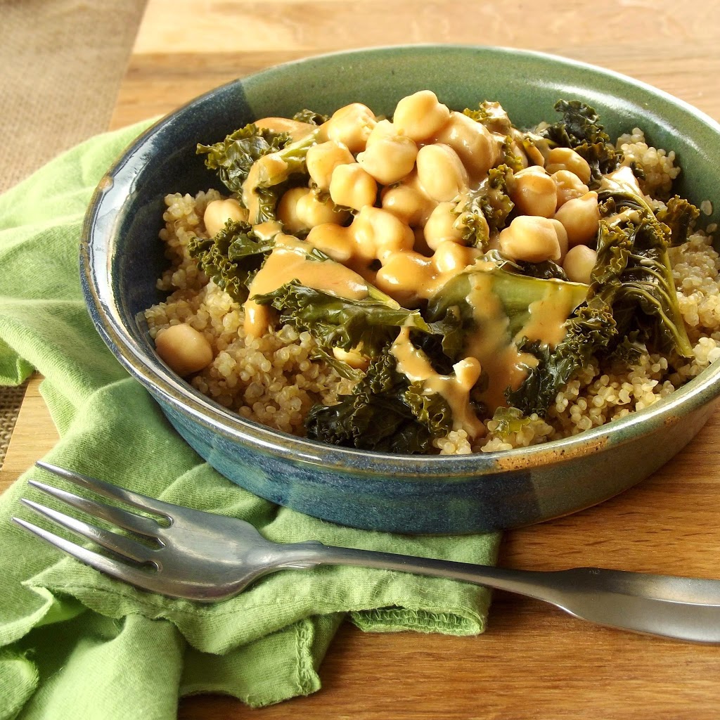 Bowl of Chickpeas, Kale and Tahini Dressing Over Quinoa on a Green Cloth, Fork in Front