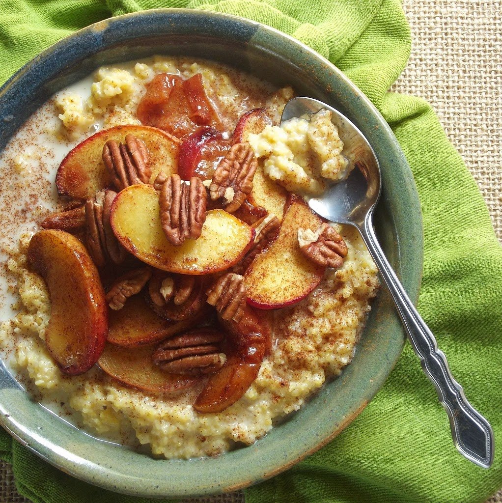 Overhead View of a Bowl of Creamy Polenta Topped with Roasted Peaches and Pecans with Spoon