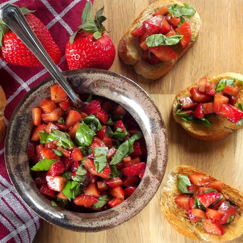 Overhead View of a Table Set with A Bowl of Strawberry Bruschetta Surrounded by Strawberries and Bruschetta Toasts