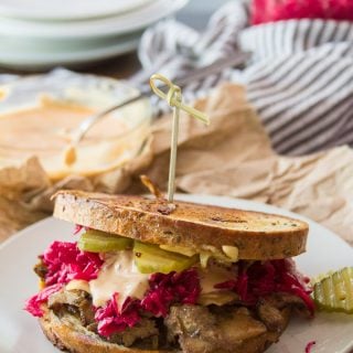 Vegan Reuben Sandwich on a Plate with Pickle Slices