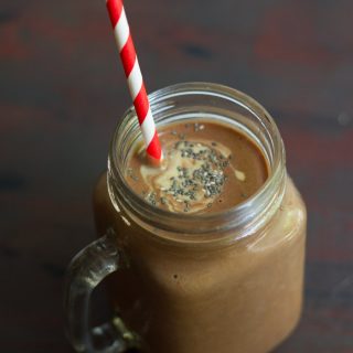 Glass Filled with Chocolate Peanut Butter Chia Smoothie with a Striped Straw and Topped with Chia Seeds