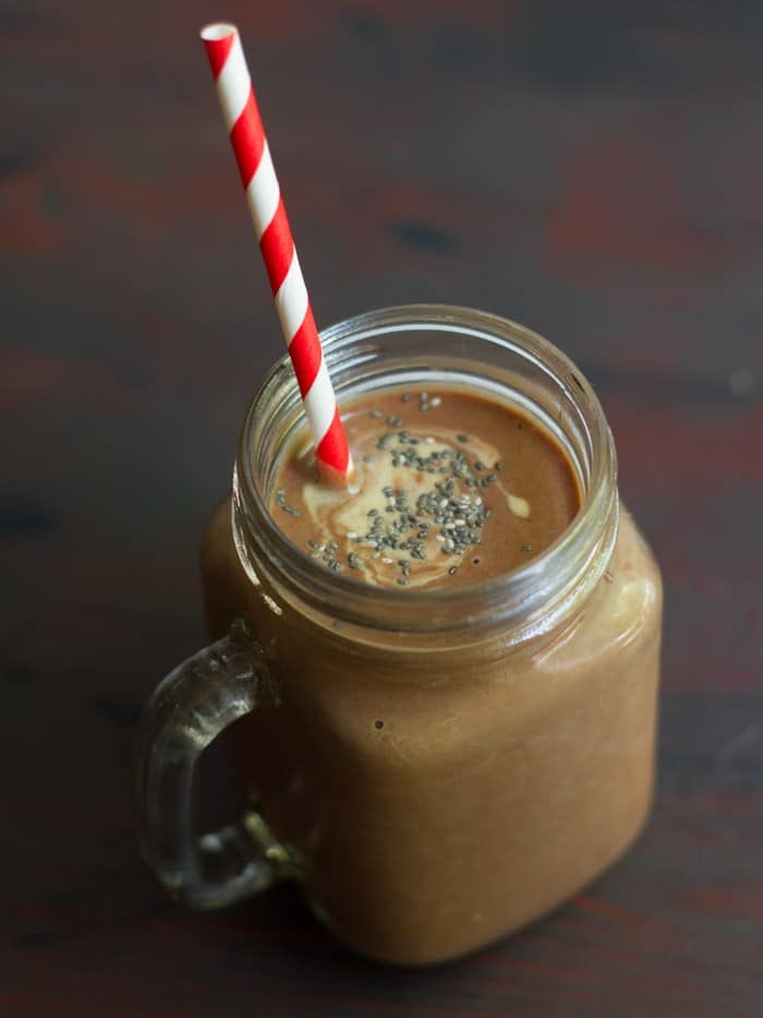 Glass Filled with Chocolate Peanut Butter Chia Smoothie with a Striped Straw and Topped with Chia Seeds