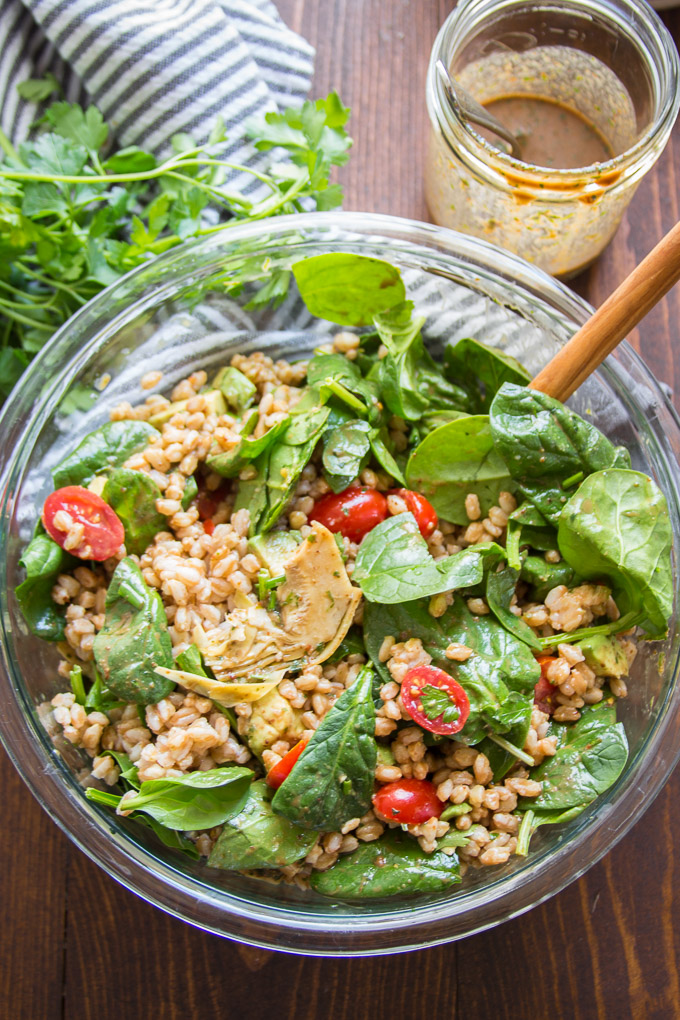 Bowl of Farro Salad with Wooden Spoon and a Jar of Balsamic Vinaigrette