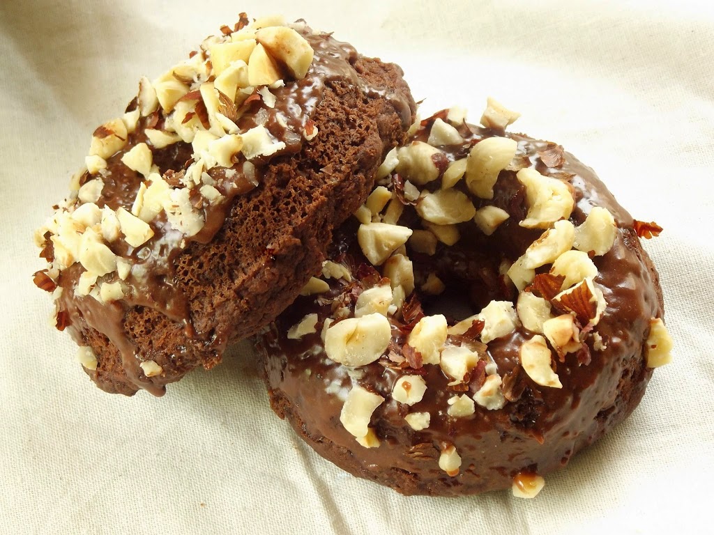 Two Chocolate Doughnuts Topped with Glaze and Chopped Hazelnuts