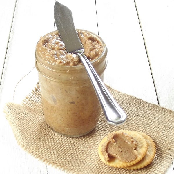 Jar of Coconut Almond Butter with Spreader on Top and Crackers in the Foreground