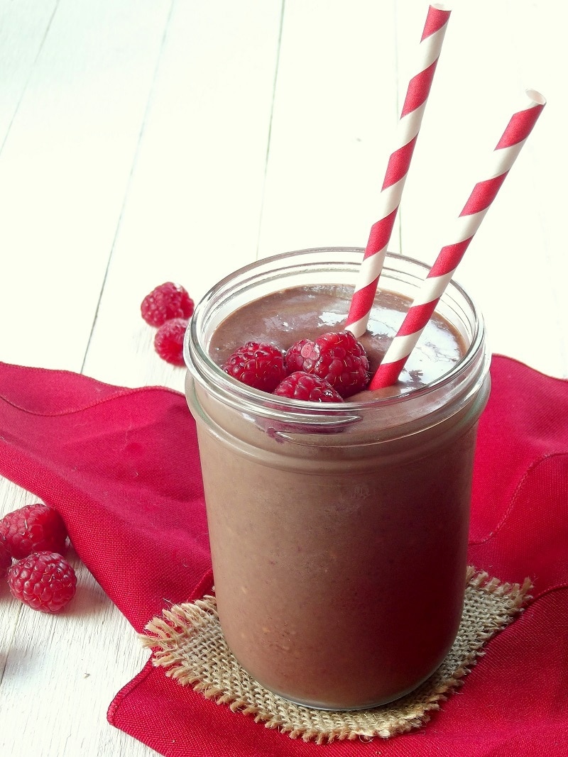 Close up of a raspberry chocolate smoothie with two striped straws.