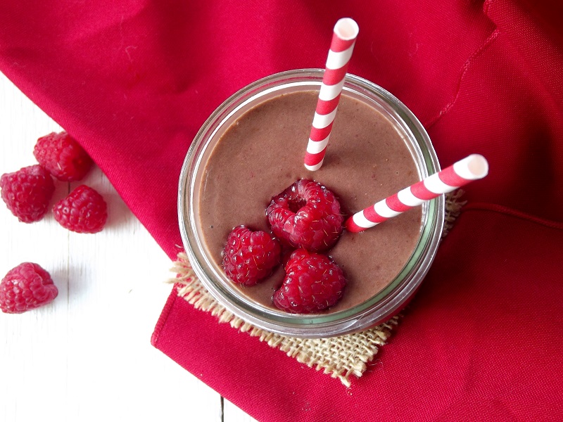 Overhead view of a raspberry chocolate smoothie with raspberries on top and on the side.