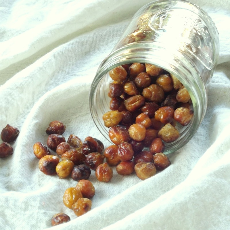 Jar of Bacon Roasted Chickpeas Spilling onto a White Cloth