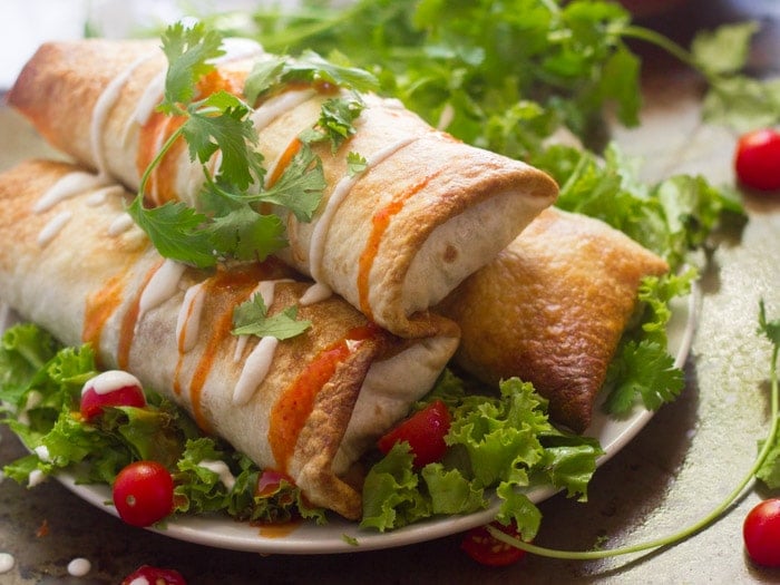 Butternut Squash & Black Bean Chimichangas on a Plate with Greens, Tomatoes and Fresh Cilantro