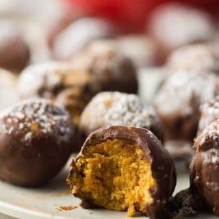 Close Up of Vegan Pumpkin Truffles on a Plate, with a Bite Taken out of One Truffle