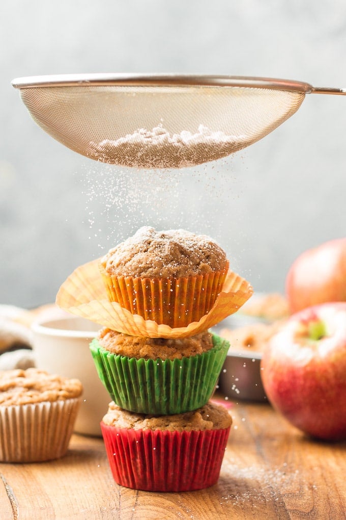 Sifter Sifting Powdered Sugar Over a Stack of Three Vegan Apple Cider Muffins