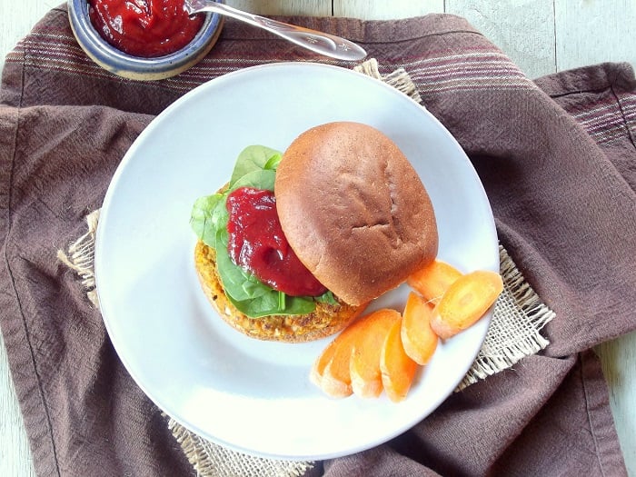Overhead view of a carrot burger on a plate with carrot slices.
