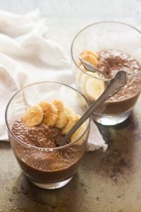 Two Glasses of Chocolate Chai Chia Pudding Topped with Cinnamon and Banana Slices