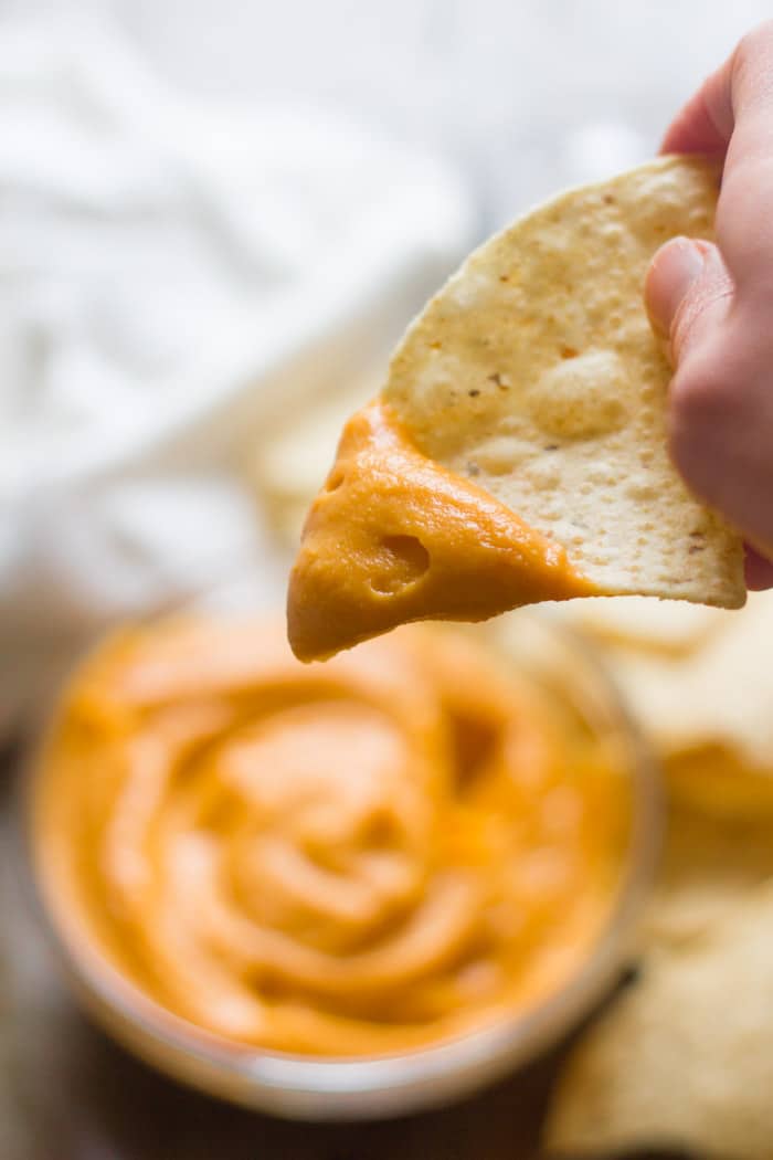 Close Up of a Hand Holding a Chip Dipped in Sweet Potato Cheese