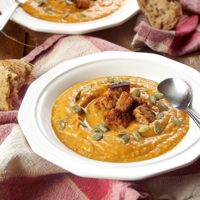 Bowl of Vegan Pumpkin Bisque Topped With Tempeh and Pumpkin Seeds