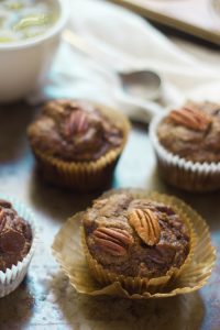 Banana Gingerbread Muffins on a Baking Sheet with Coffee Cup in the Background