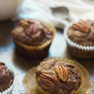 Banana Gingerbread Muffins on a Baking Sheet with Coffee Cup in the Background