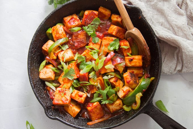 Vegan Chilli Paneer in a Cast Iron Skillet with a Wooden Spoon
