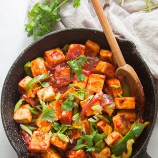 Skillet Filled with Vegan Chilli Paneer Topped with Scallions and Cilantro