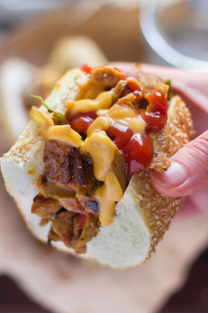 Hand Holding Half of a Vegan Philly Cheesesteak Sandwich