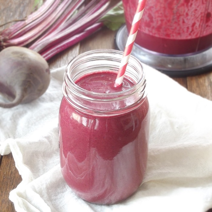 Beet Smoothie in a Glass with Striped Straw, Blender and Bunch of Beets in the Background