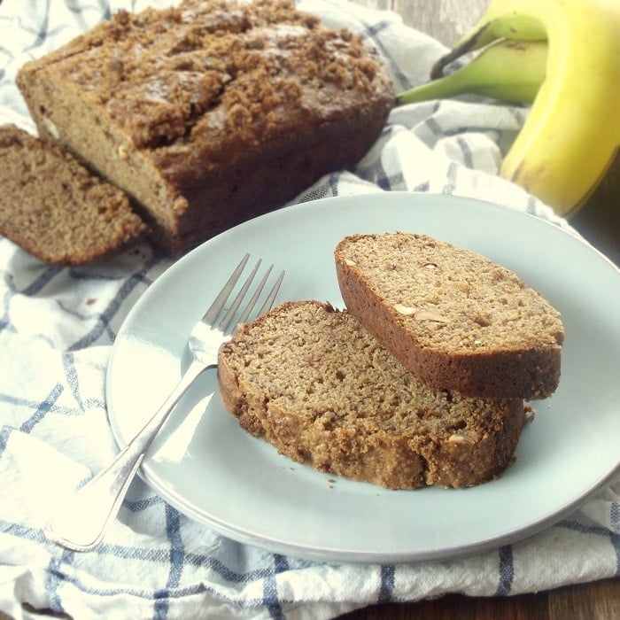 Plate Containing Two Slices of Peanut Butter Banana Bread and Fork, Bananas and Loaf in the Background