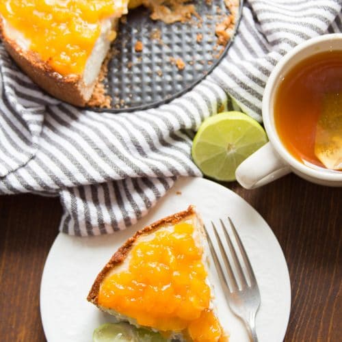 Overhead View of a Slice of Vegan Cheesecake with Mango Lime Topping on a Plate with Teacup