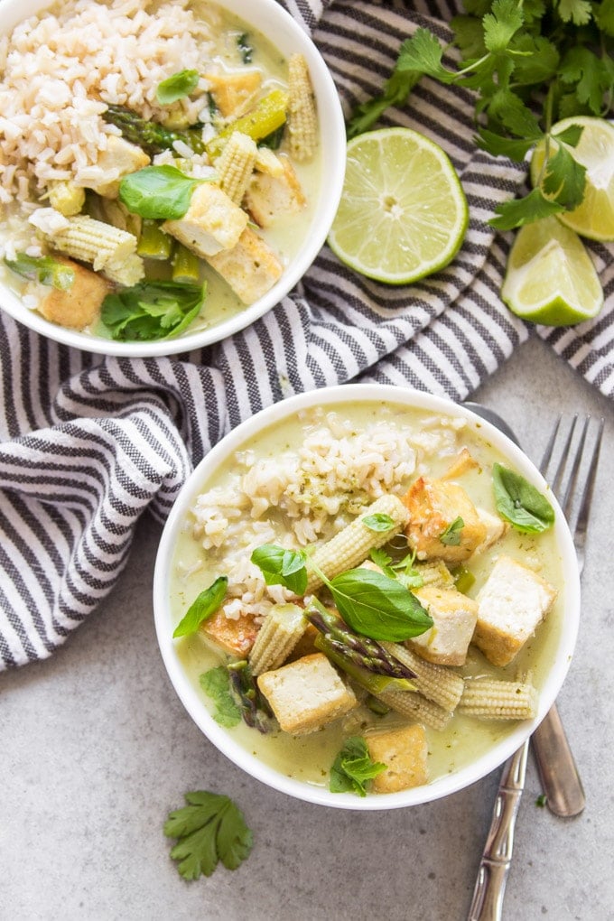 Two Bowls of Vegan Green Curry with Napkin and Lime Wedges