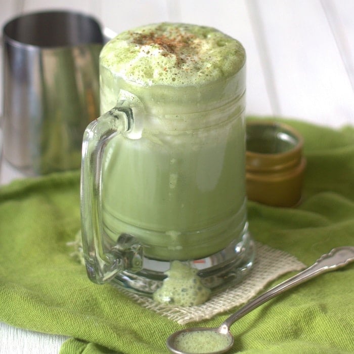 Matcha Latte in a Glass Mug Sitting on a Green Napkin with Spoon
