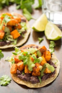 Two Sweet Potato Tostadas and Lime Wedges on a Baking Sheet