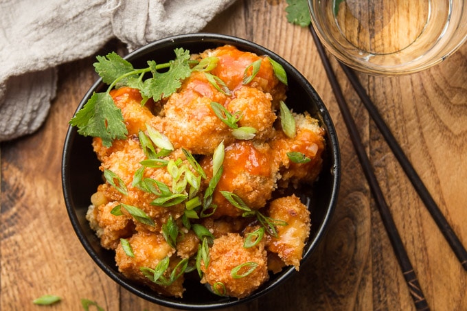 Overhead View of a Bowl of Baked Cauliflower Manchurian with Chopsticks and Water Glass on the Side