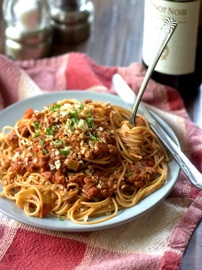 Plate of Vegan Spaghetti Bolognese with Wine Bottle in the Background